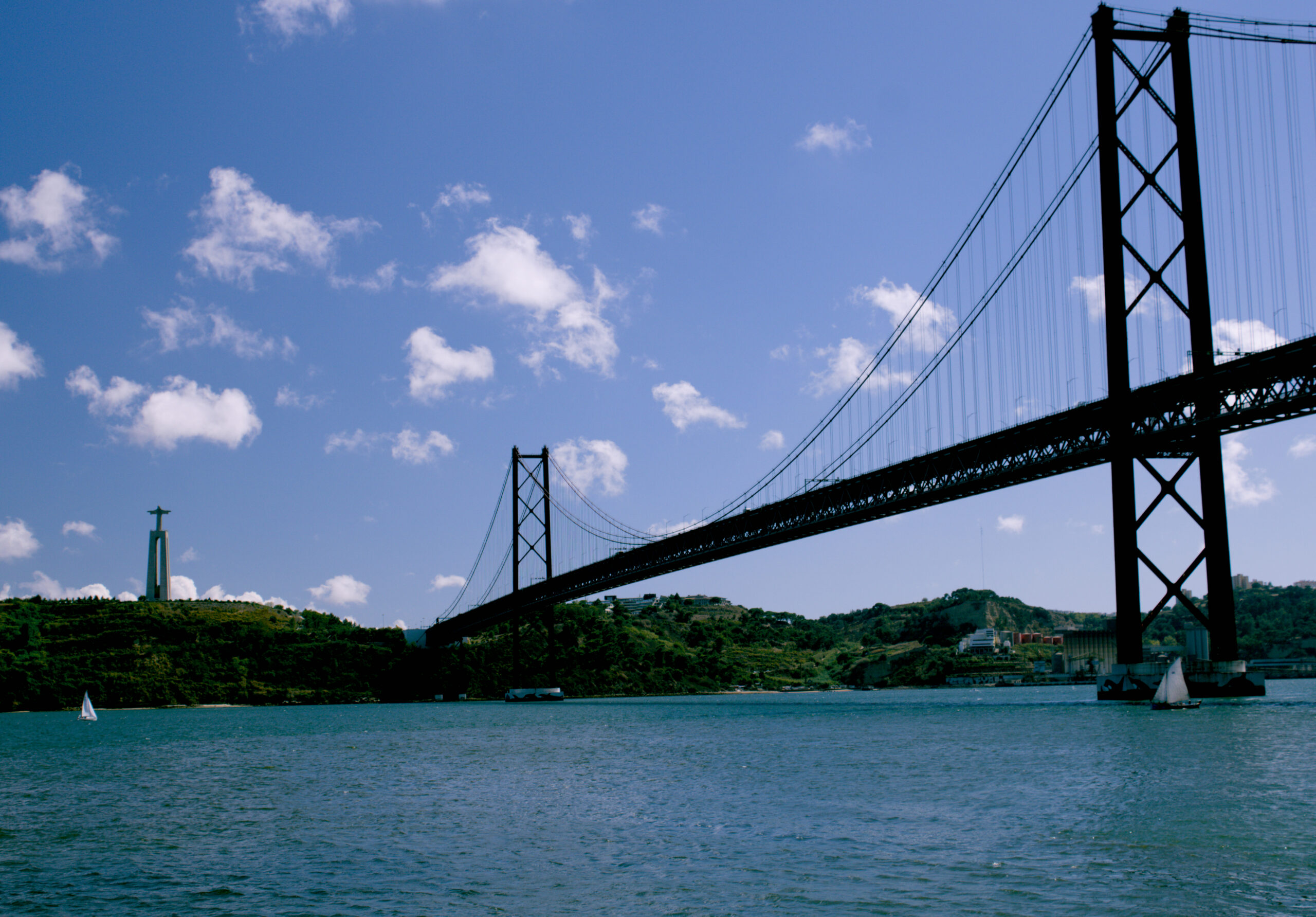 Ponte 25 de Abril destacada contra o céu azul com nuvens — ícone de Lisboa em composição arquitetónica